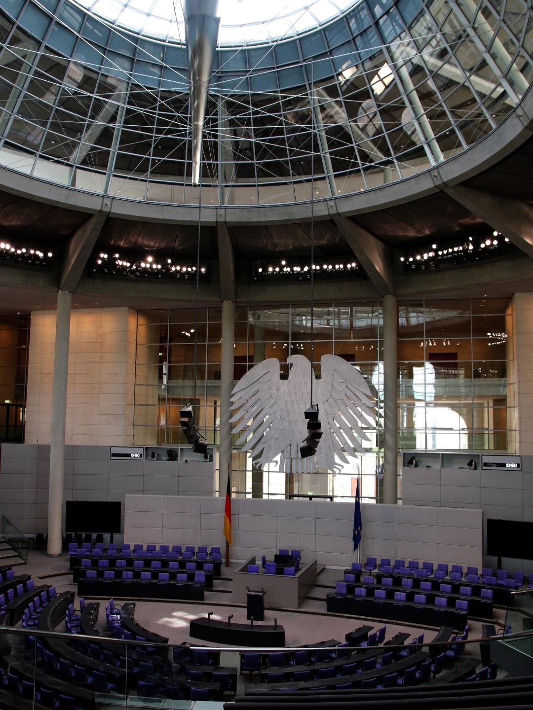 Plenarsaal des Deutschen Bundestages in Berlin mit dem Bundesadler. Besuchergruppen erleben hier die parlamentarische Arbeit bei einem Besuch im Bundestag.